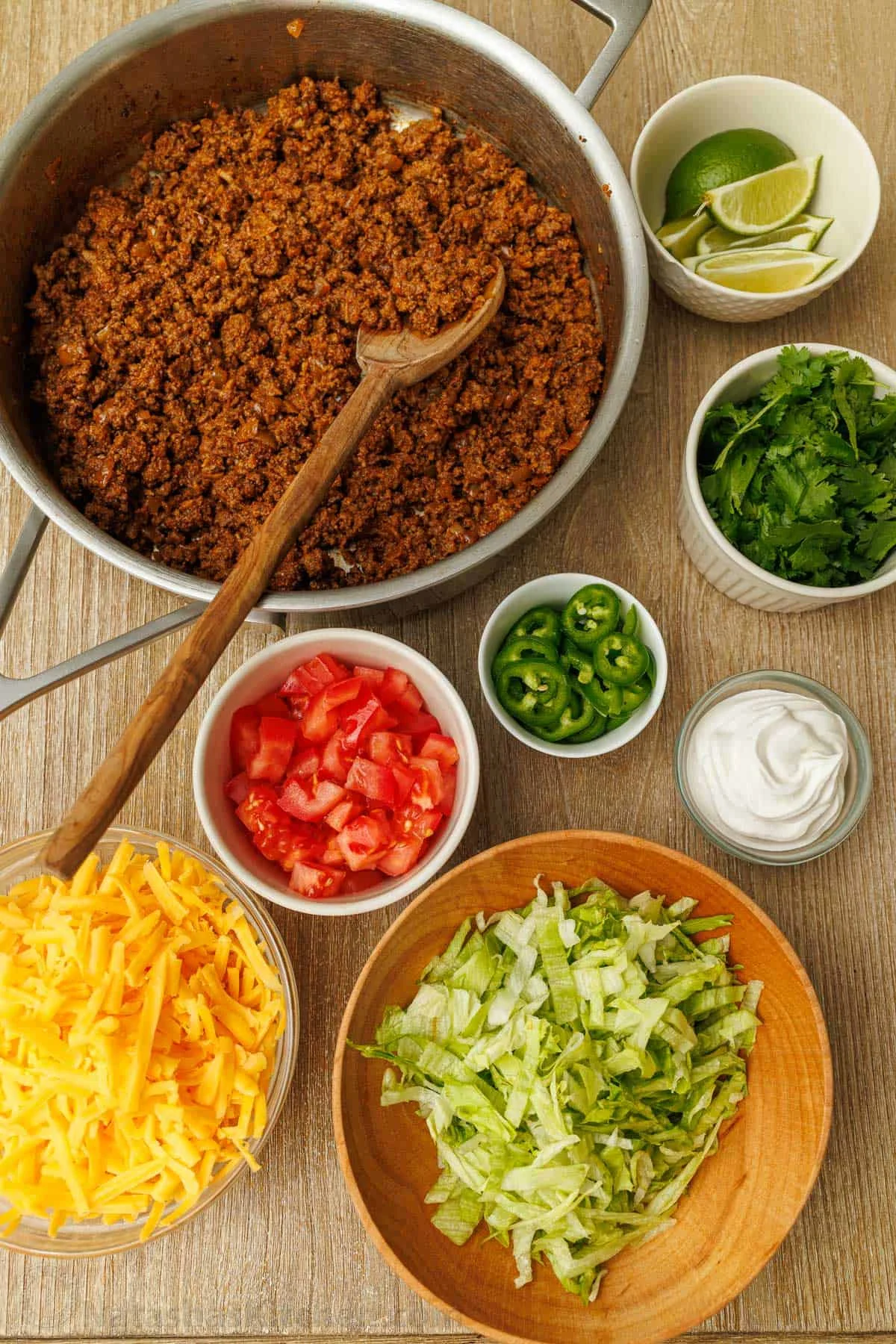 Overhead of a taco bar with seasoned beef and fresh toppings