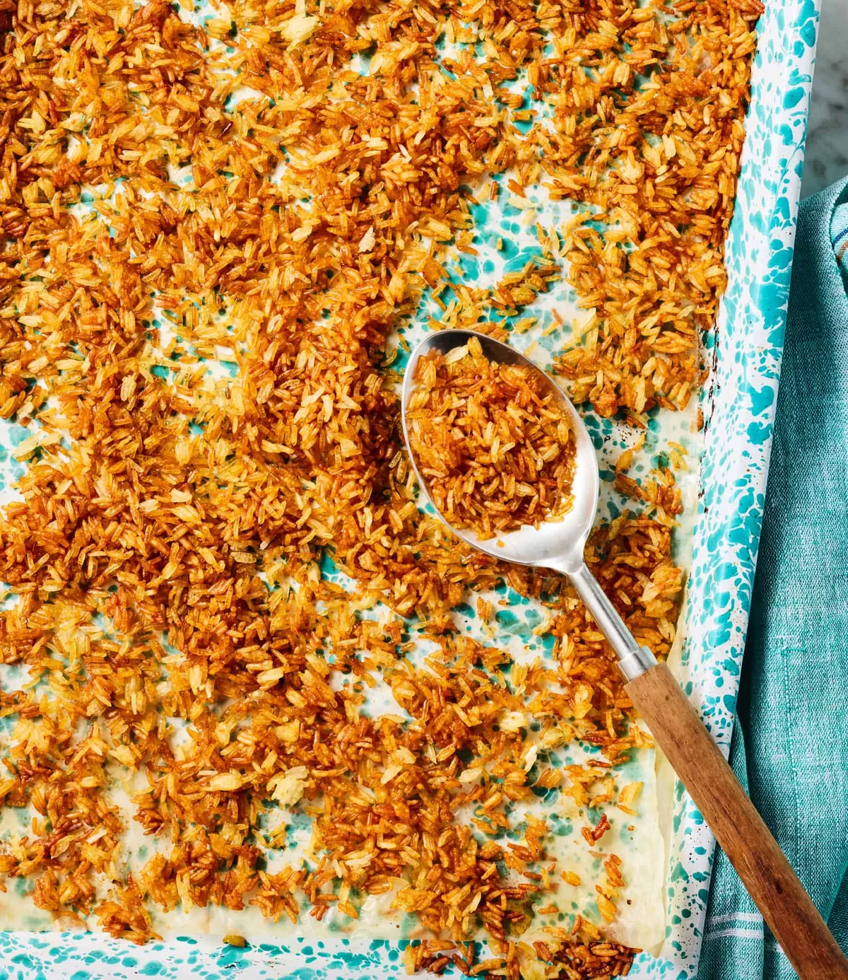 Golden-brown crispy rice in a teal dish, top shot