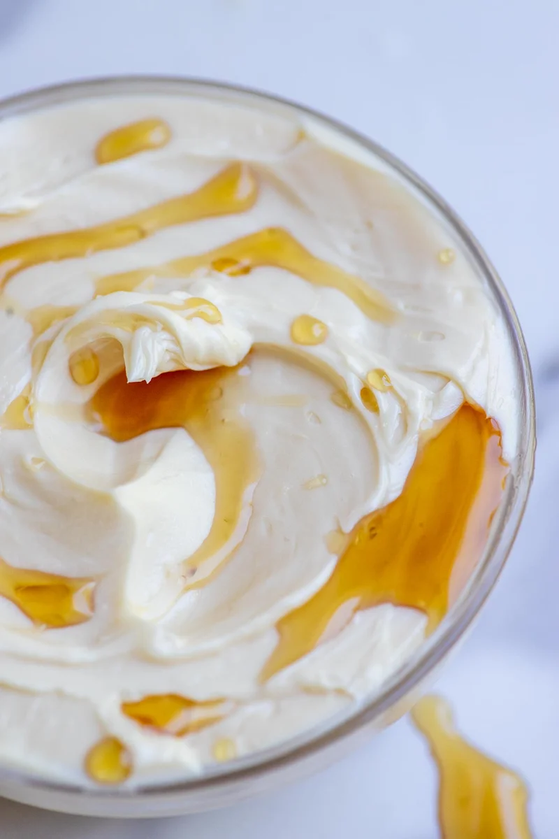 Whipped maple butter in a glass bowl drizzled with maple syrup