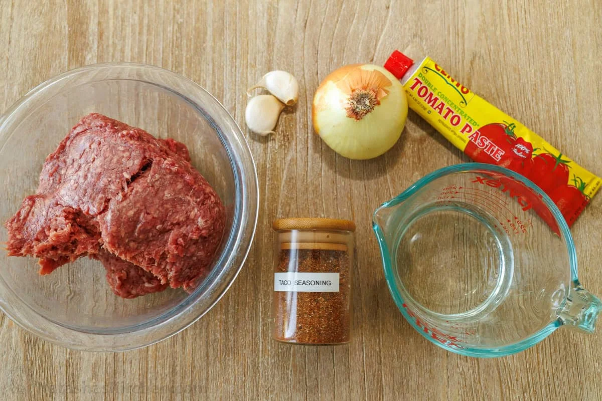 Flat-lay of ground beef, onion, garlic, tomato paste, seasoning