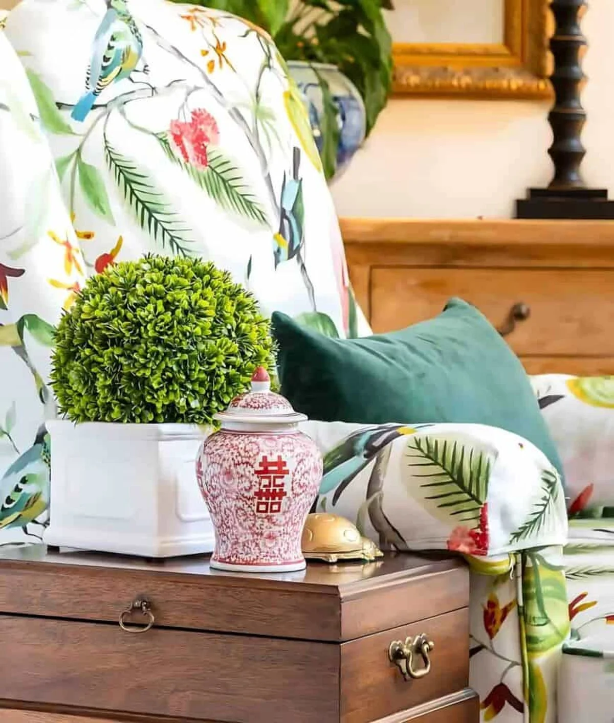Boxwood topiary and a red vase on a wooden nightstand