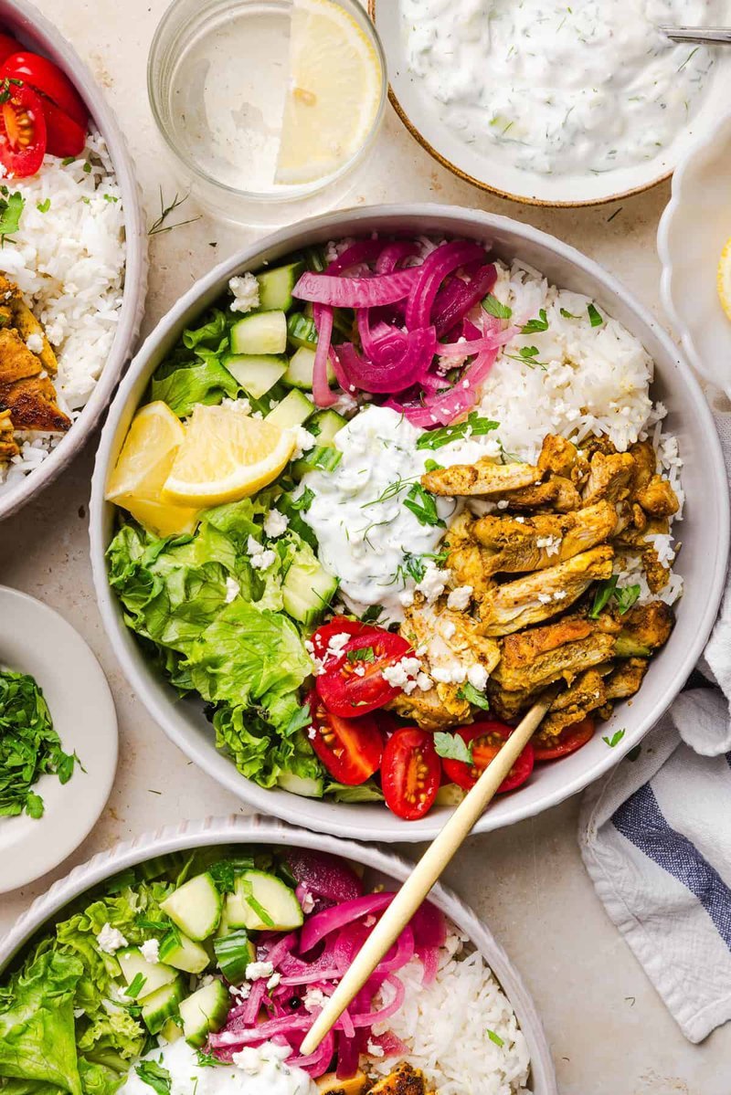 Styled shawarma bowls with lemon wedges and side salad on table