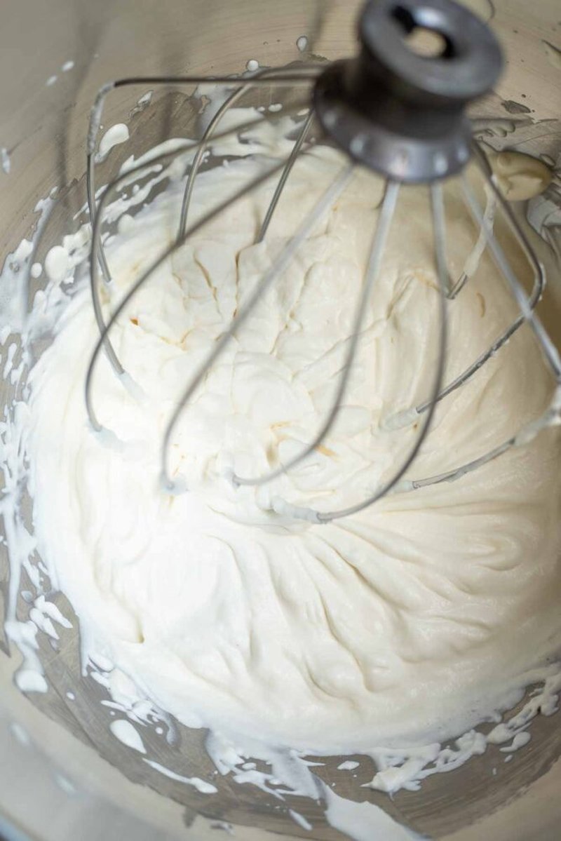 Whisk attachment lifted from cream, showing a firm stiff peak