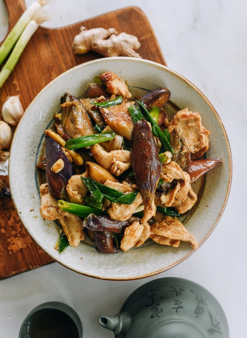 Hand slicing Cantonese eggplant on a wooden board