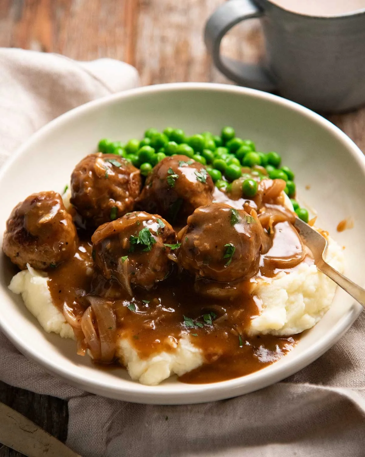 Pork meatballs nestled in onion gravy in a bowl