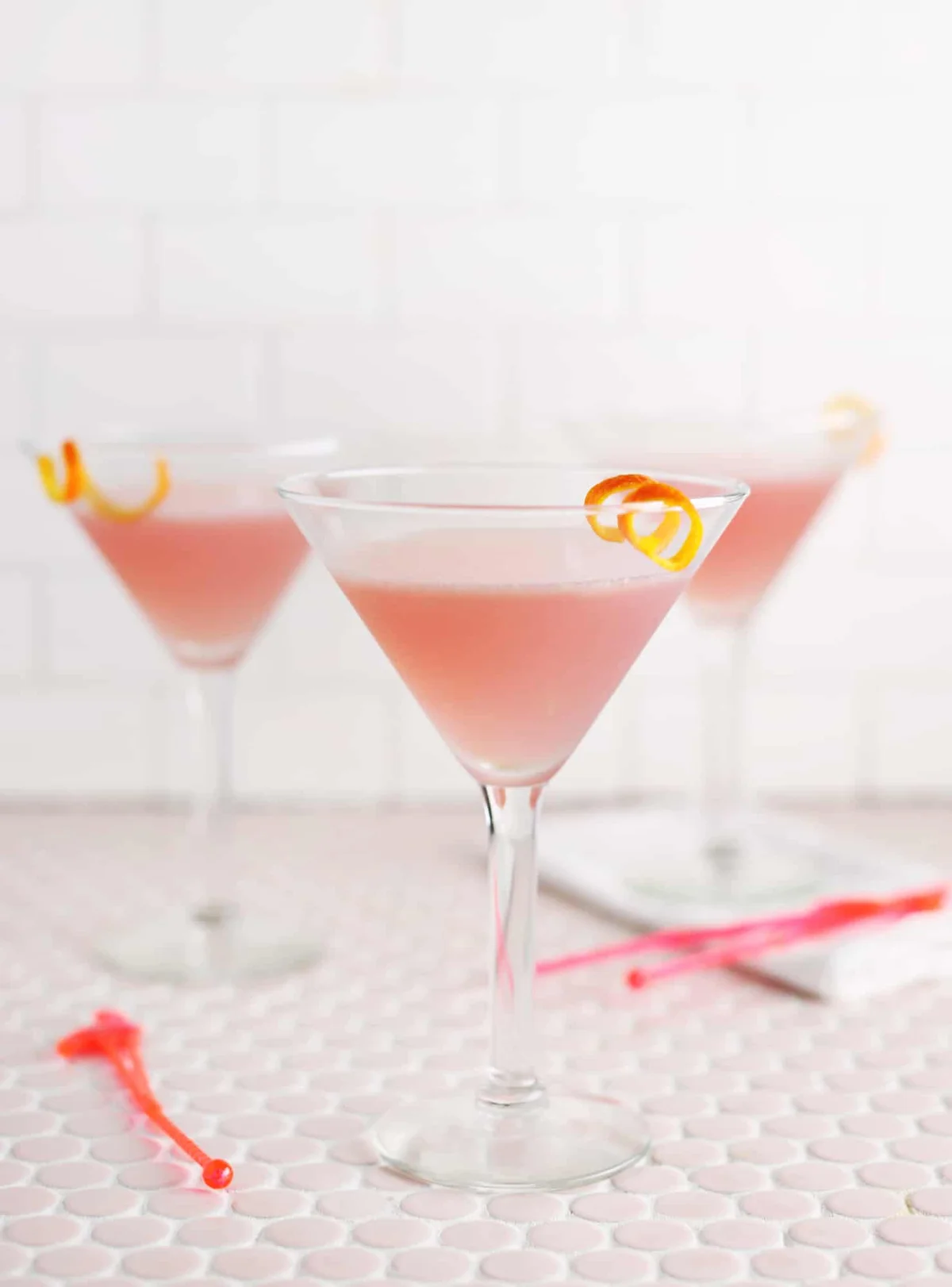 Pink Cosmopolitan cocktail in a stemmed martini glass on pink tile