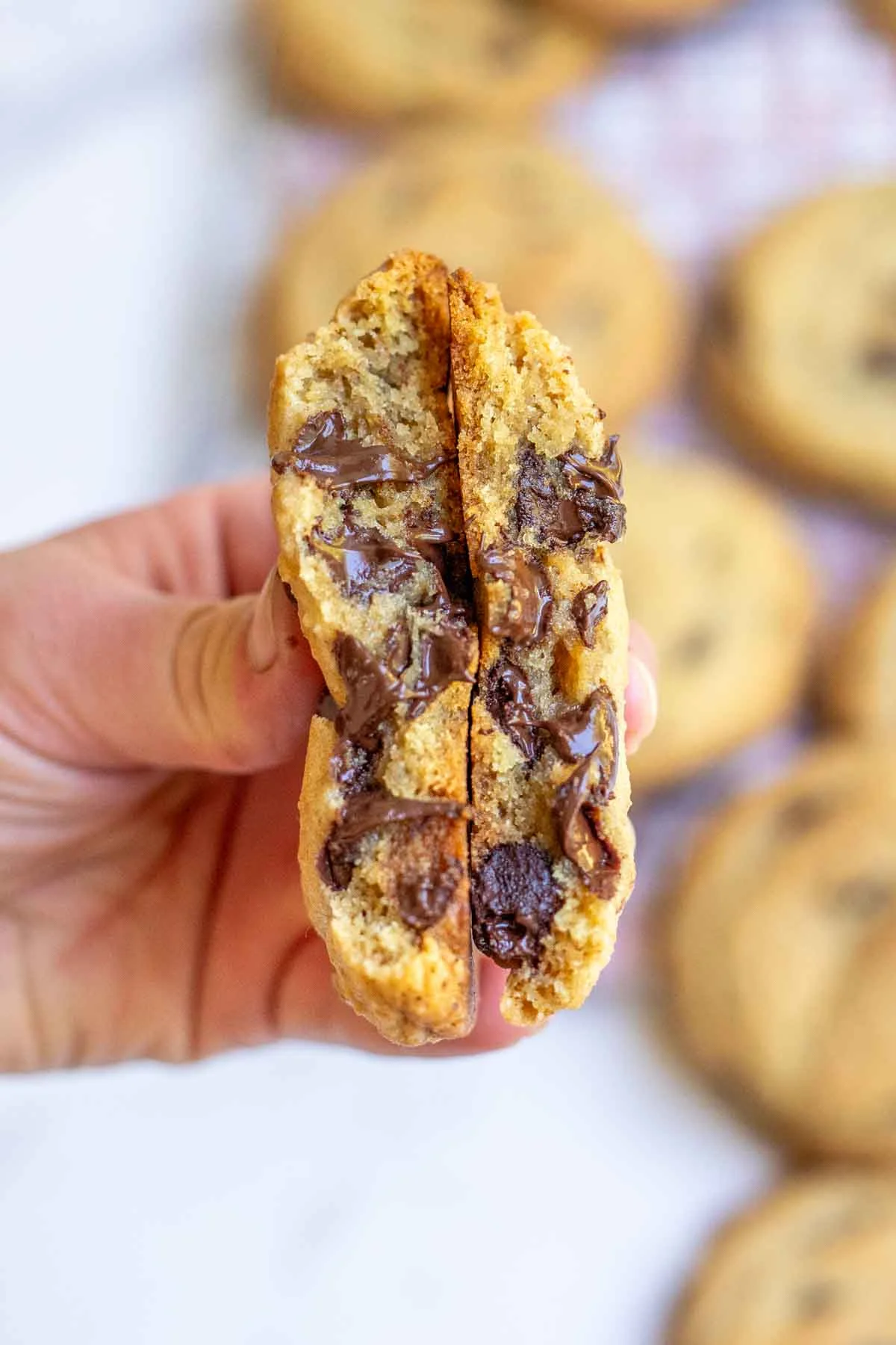 Broken open cookie showing soft chewy interior and melty chocolate