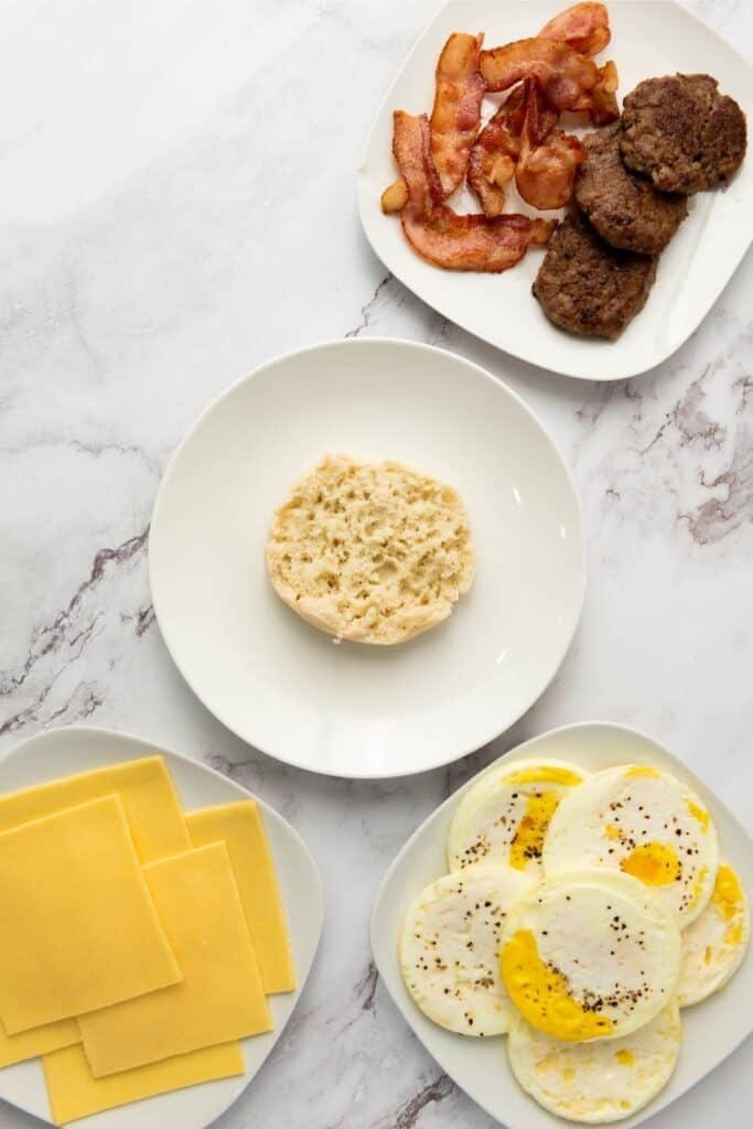 Six assembled breakfast sandwiches on a white platter