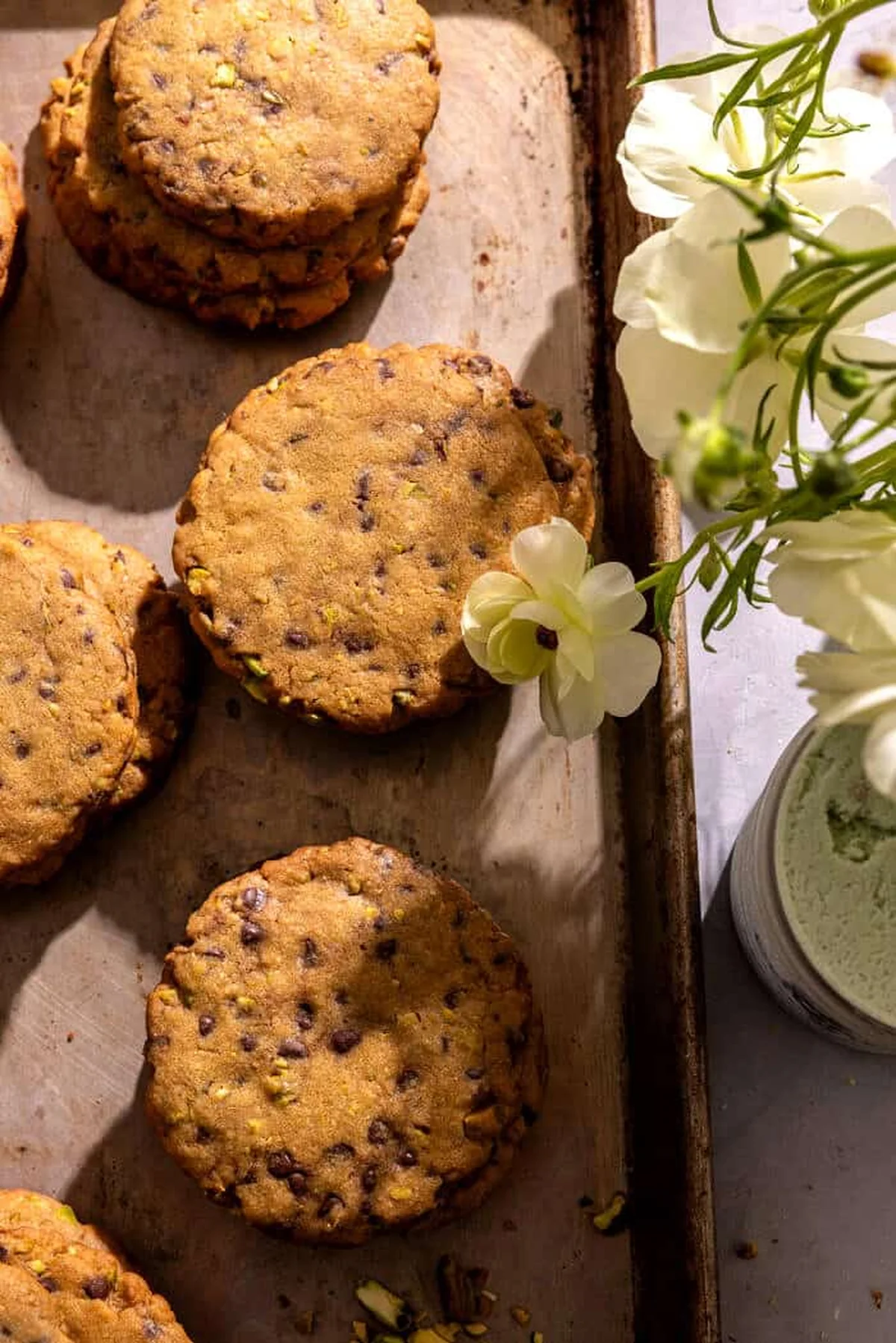 Baked pistachio chocolate chip cookies cooling on a baking sheet