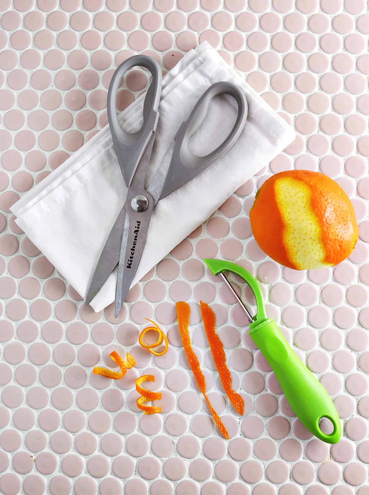 Kitchen shears, peeler, and curled orange peel strips for the garnish
