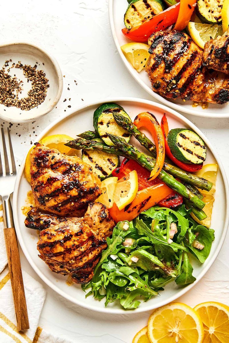 Overhead plates of grilled chicken with charred vegetables and salad