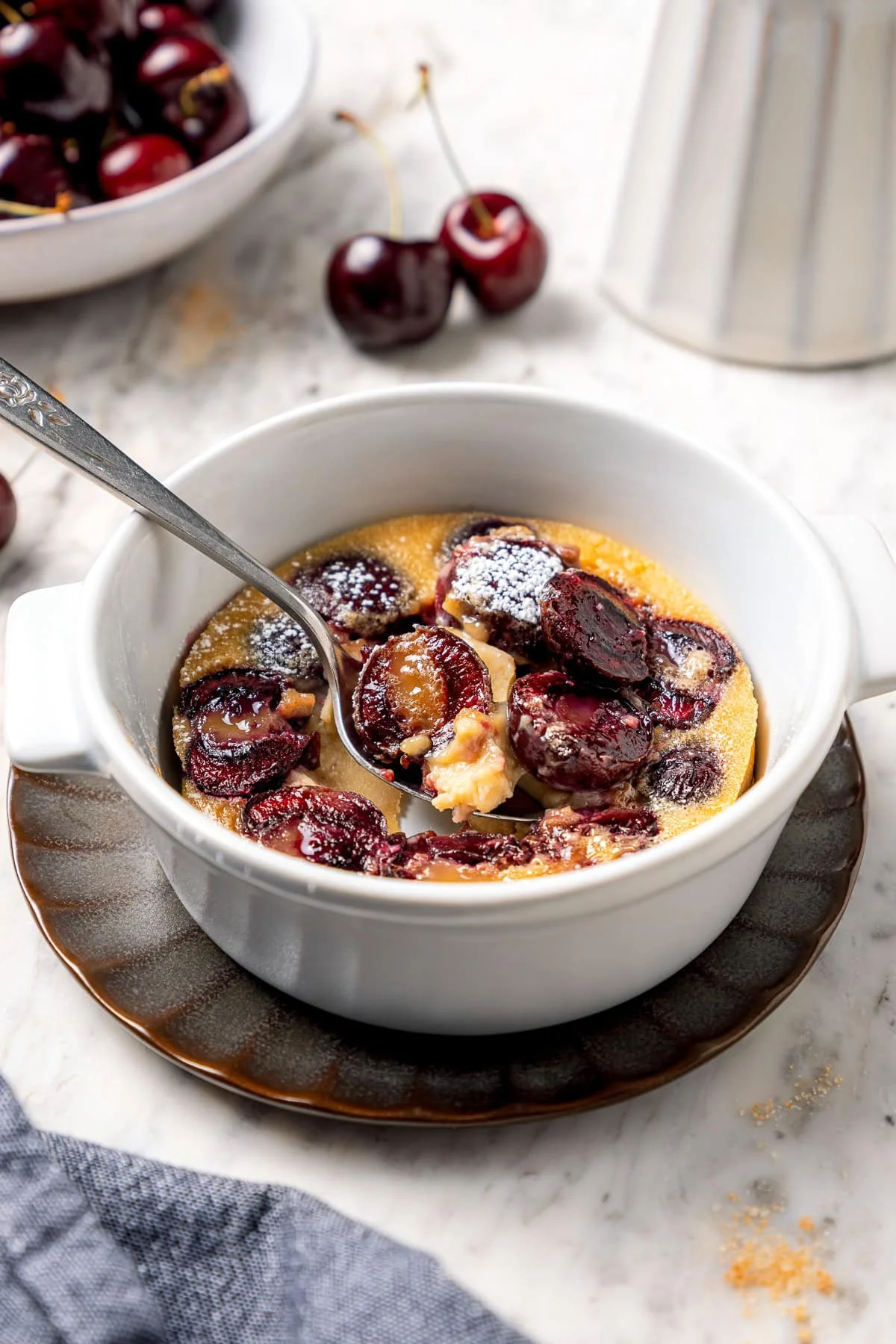 Baked clafoutis in ramekins dusted with powdered sugar