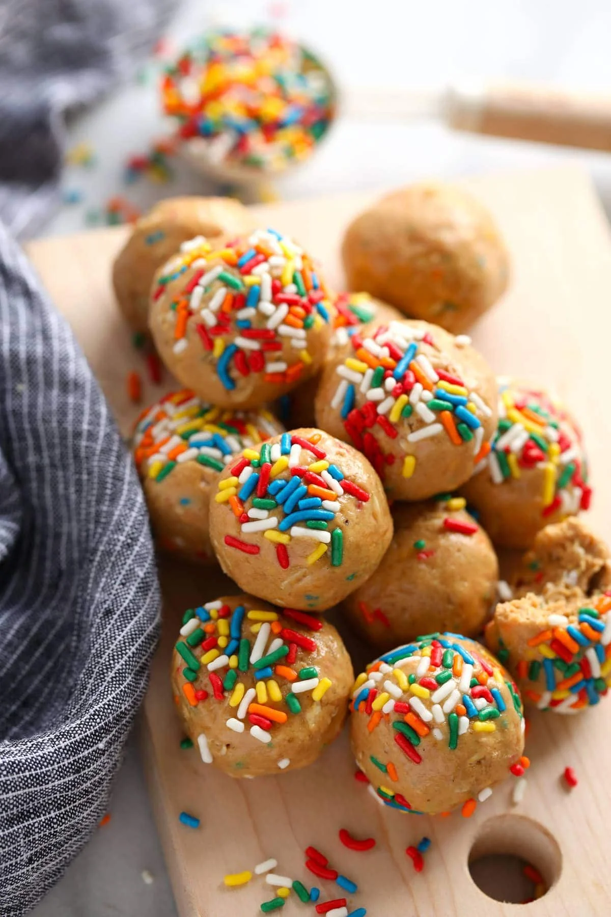 Pile of birthday cake protein balls with rainbow sprinkles on a wooden board